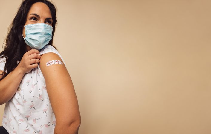 Woman wearing protective face mask received a coronavirus vaccine on her arm