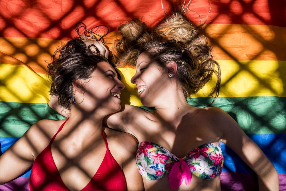 Lesbian couple lying on rainbow flag