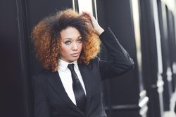 Female in suit outside adjusting her hair on street, copy space