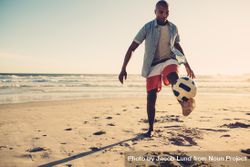 Young man playing soccer at the seaside bGNDx4