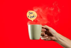Hand holding a steaming coffee mug with "take a break" message on red background.