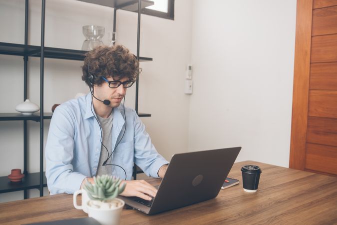 Male telemarketing with head set in front of laptop and working at home