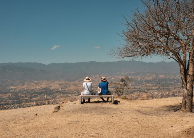 Back of two people on bench over looking hills in Mexico