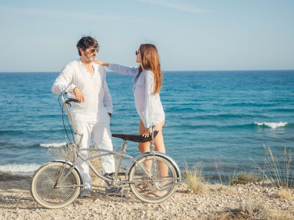 Man and woman holding bicycle at seaside