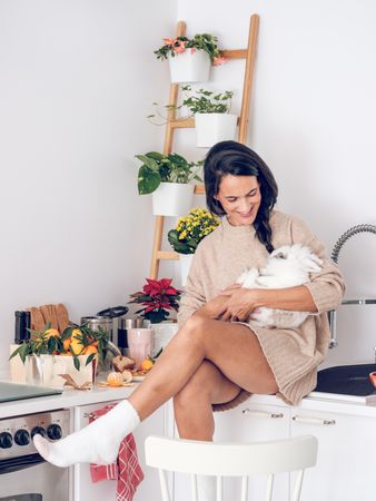 Smiling woman hugging rabbit in kitchen