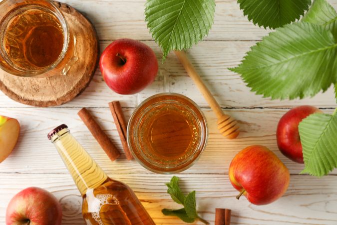Composition with cider, cinnamon and apples on wooden background