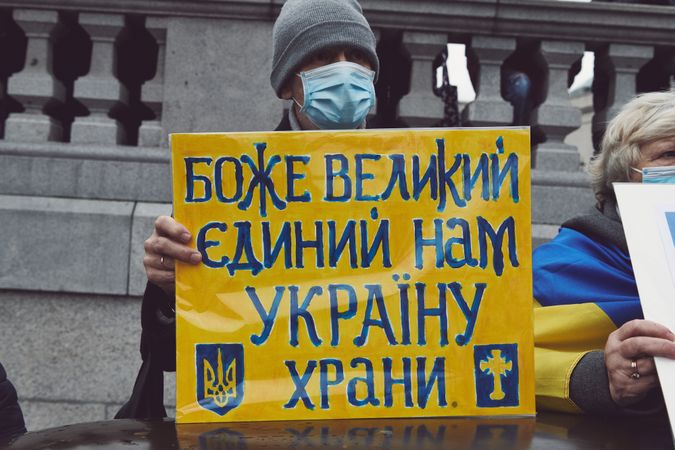 London, England, United Kingdom - March 5 2022: Man holding blue and yellow sign with Cyrillic