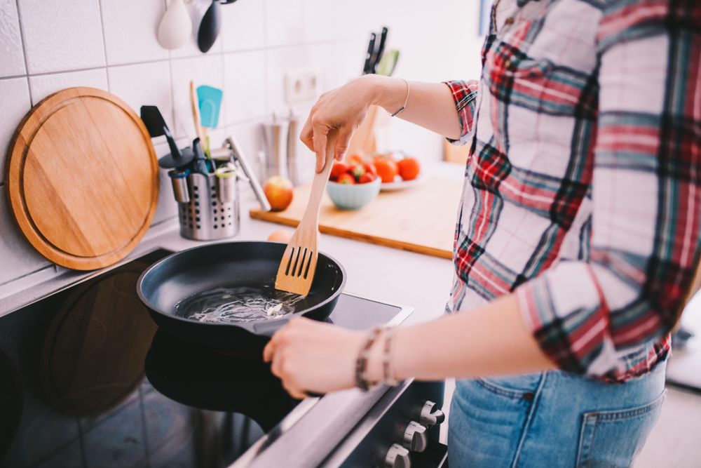 Woman standing over a stove pre-heating a pan