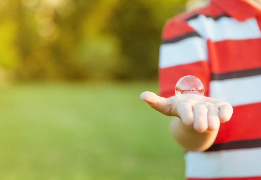 Cute boy showing soap bubble in his open hand