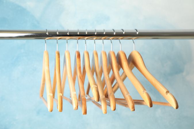 Hangers on rod against blue background, space for text