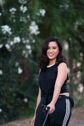 Woman with dark athletic attire smiles at camera while holding dog leash