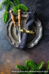 Dark plate with knife and fork with pine branch and napkin with golden ring 0gEMM4