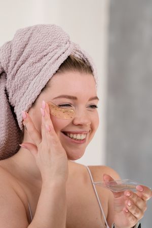 Applying eye patches in skincare routine.