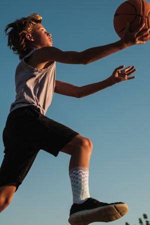 Active boy throwing basketball in hoop
