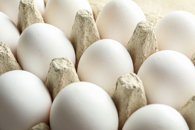 chicken eggs in carton box on wooden table, closeup