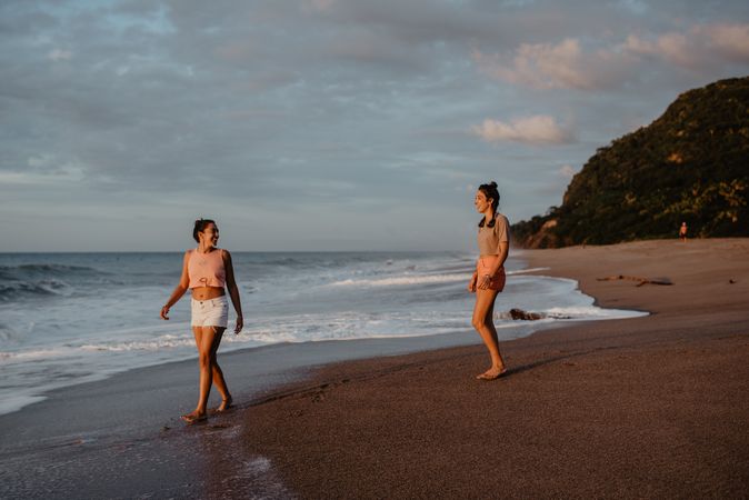 Smiling women looking at each other on beach