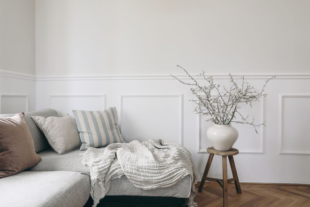 Stylish living room with vase and blooming cherry plum tree branches