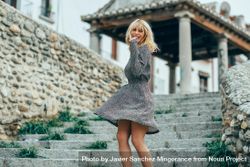 Blonde woman in floral dress turning around and dancing on cement staircase outside 4d2aa0