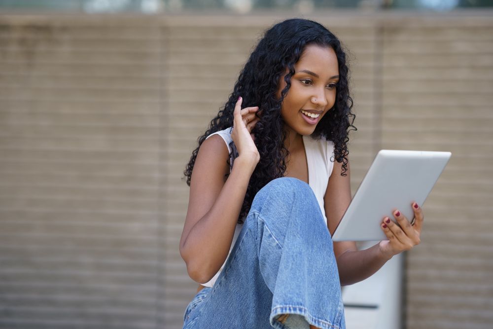 A young woman joyfully engages in a video call on her tablet, enjoying meaningful connections