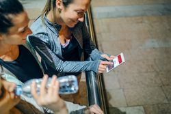 Top view of happy women runners checking activity summary on tracker phone app