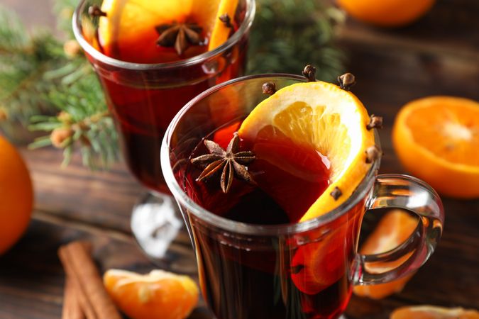 Glasses of tasty mulled wine with orange on wooden background, close up