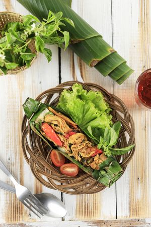 Top view of nasi bakar ayam suwir with kemangi, steamed rice with stir fry spicy shredded chicken