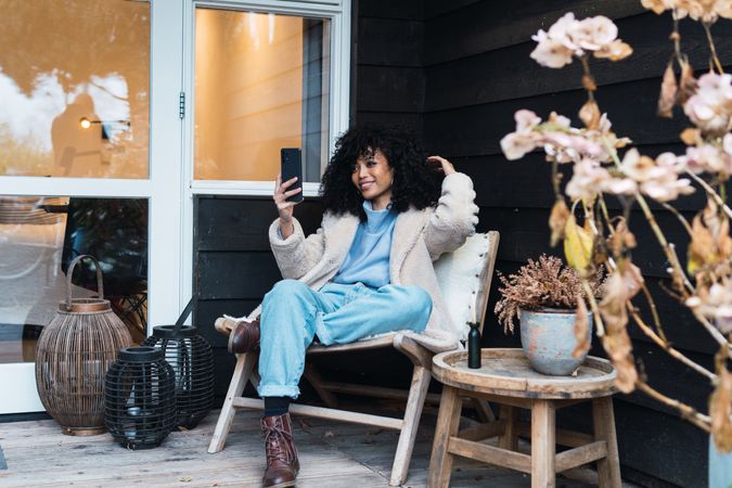 Cheerful Black woman browsing smartphone on terrace