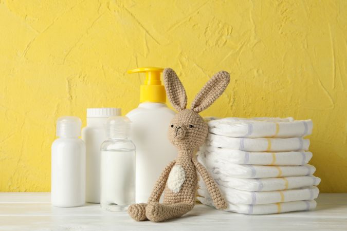 Baby hygiene accessories on wooden table against yellow background
