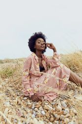 Woman in pink floral dress sitting on brown grass field