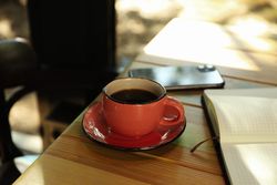 Cup of coffee, notebook and phone on wooden table