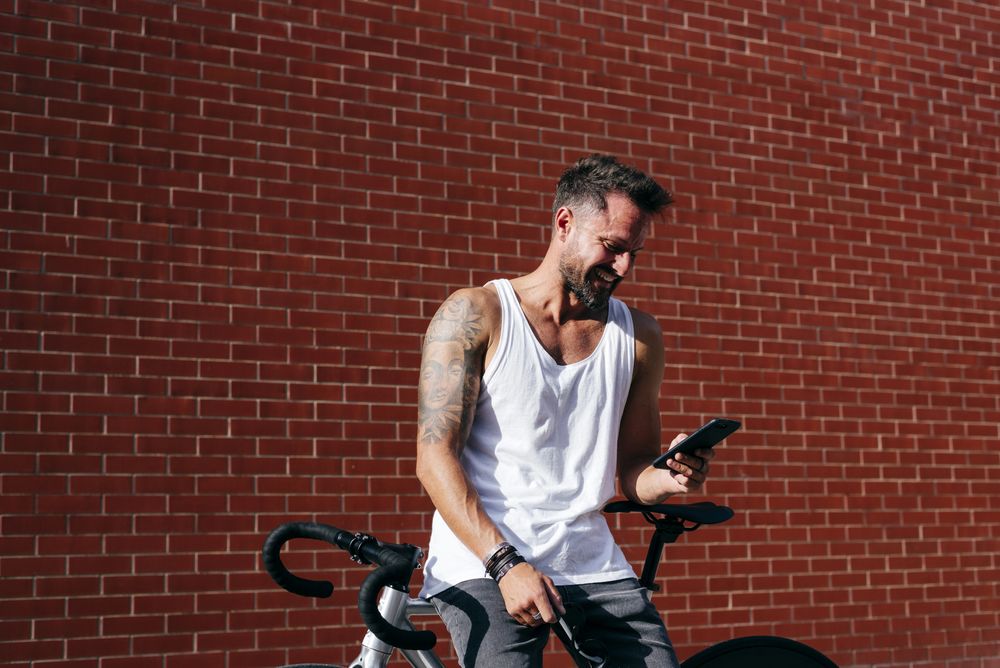 Sportive man with bicycle using phone