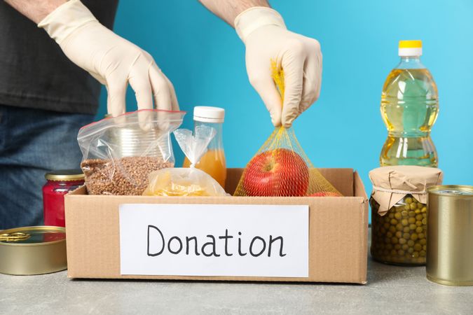 Young man puts groceries in donation box. Volunteer