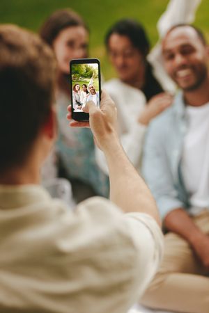 Close-up of a man using cell phone for photographing friends at the picnic