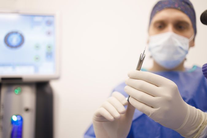 Doctor holding surgery tools while wearing latex gloves