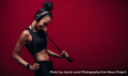 Smiling woman with a jumping rope over red background 41xxO5