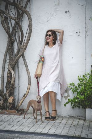 Cheerful female standing with dog near street wall