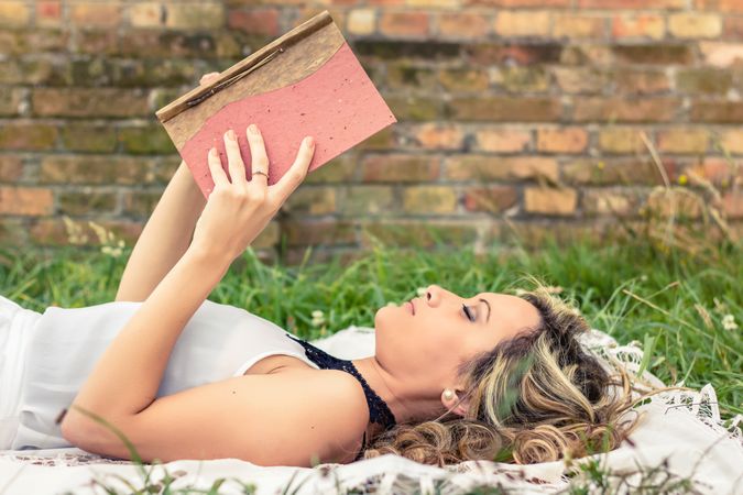 Romantic woman reading a book lying outdoors