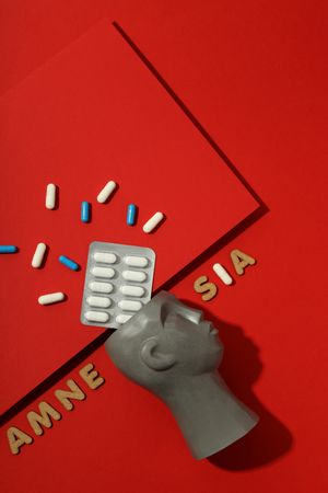 Vertical composition of bust with pills and the words “Amnesia” copy space