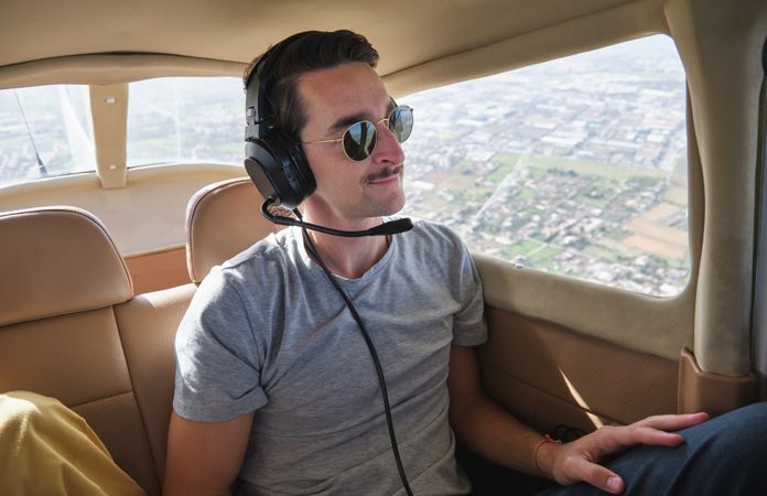 Smiling young male passenger flying over city in aircraft