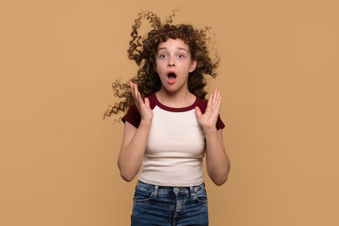 Young girl with hair blowing upwards, expressing surprise