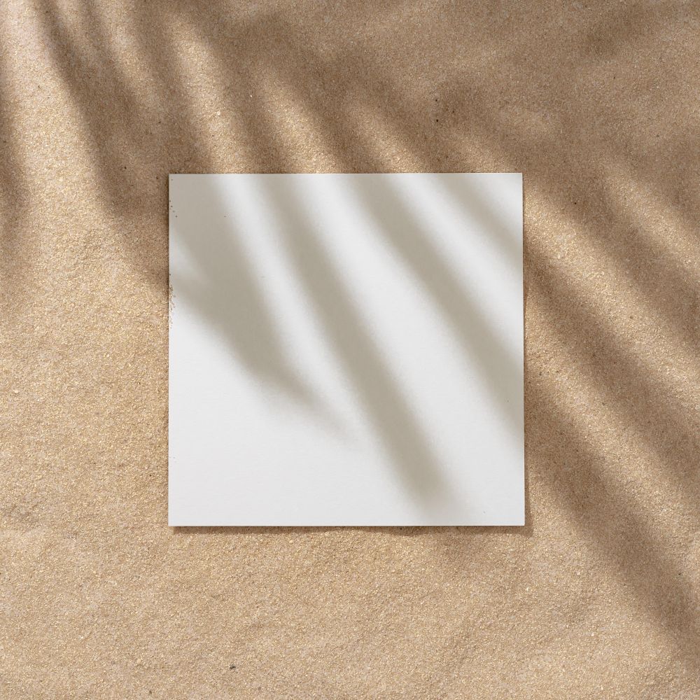 Sand with palm leaf shadows and central square