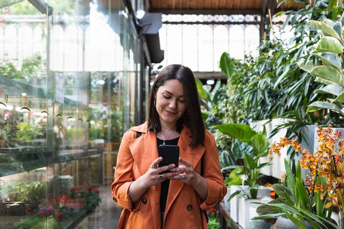 Content woman using the cellphone in garden center