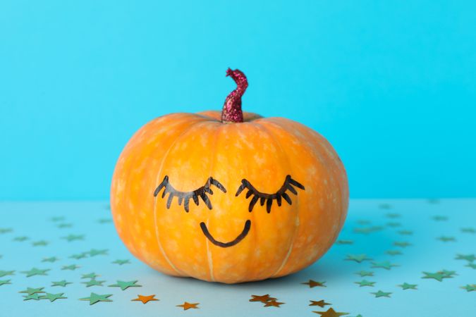 Pumpkin with smile on blue decorative background, space for text