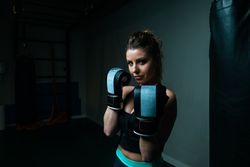 Sportswoman in boxing gloves in gym