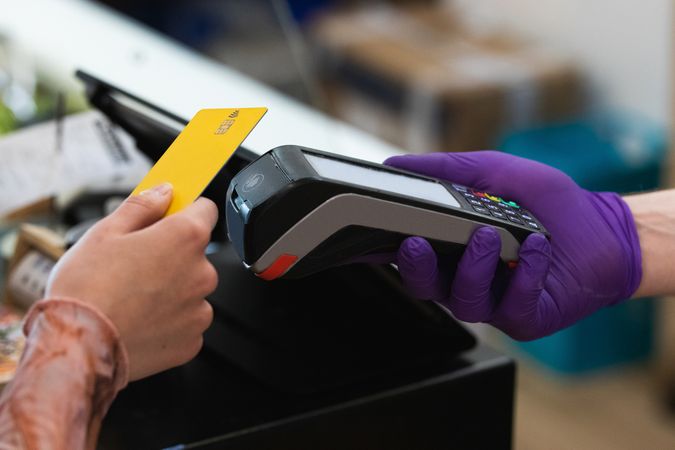 Crop woman paying with plastic card on terminal