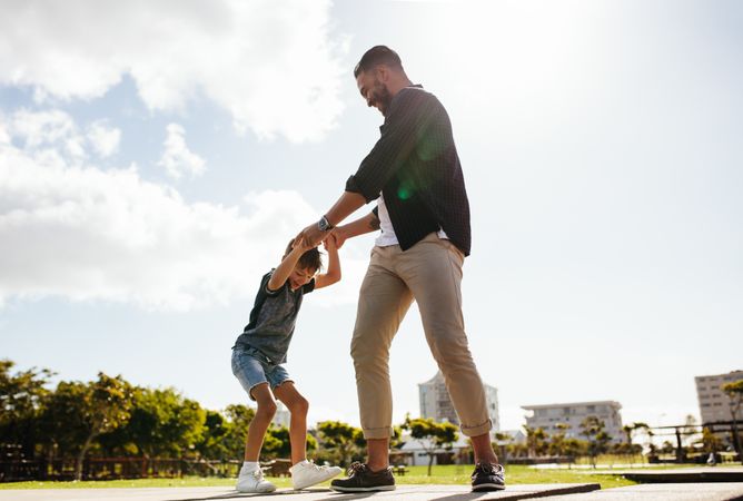 Cheerful man playing with his son at a park