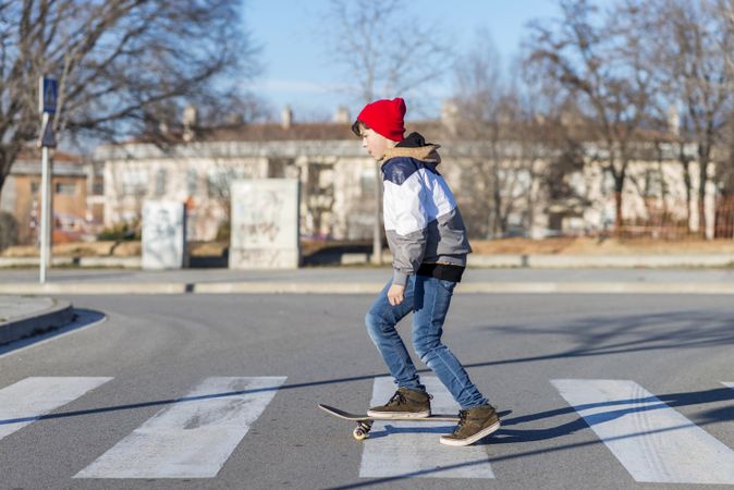 Teenage skateboarder crossing the street on board