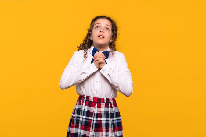Girl looking up with hands clasped