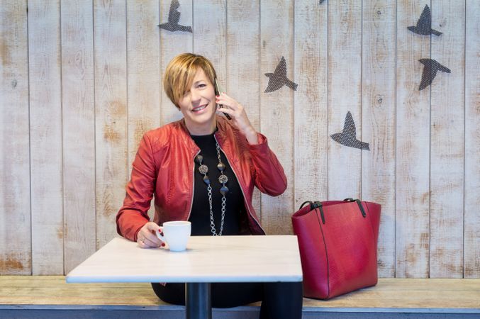 Business woman dressed in red speaking on phone in restaurant
