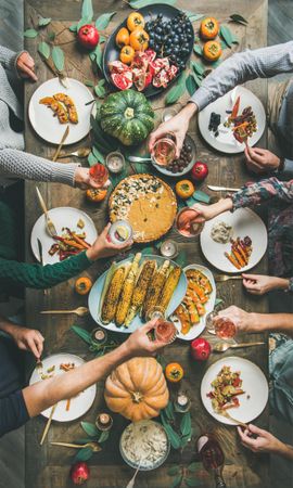 Group of people with wine glasses over festive vegetarian table with pie, vertical composition